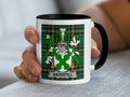 White mug with black rim featuring Ancketill family crest on plaid background.