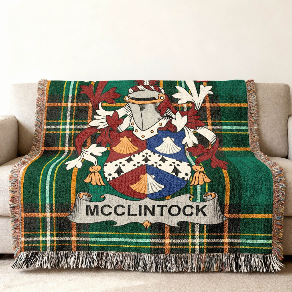 Woven throw blanket with green plaid and a coat of arms bearing the name MCCLINTOCK.