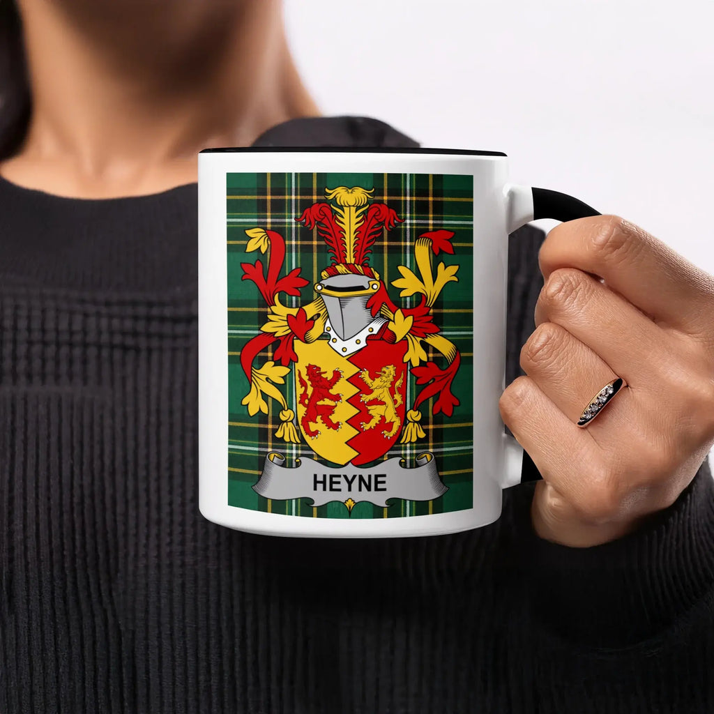 Mug with Heyne family crest on green plaid background, held by a person.