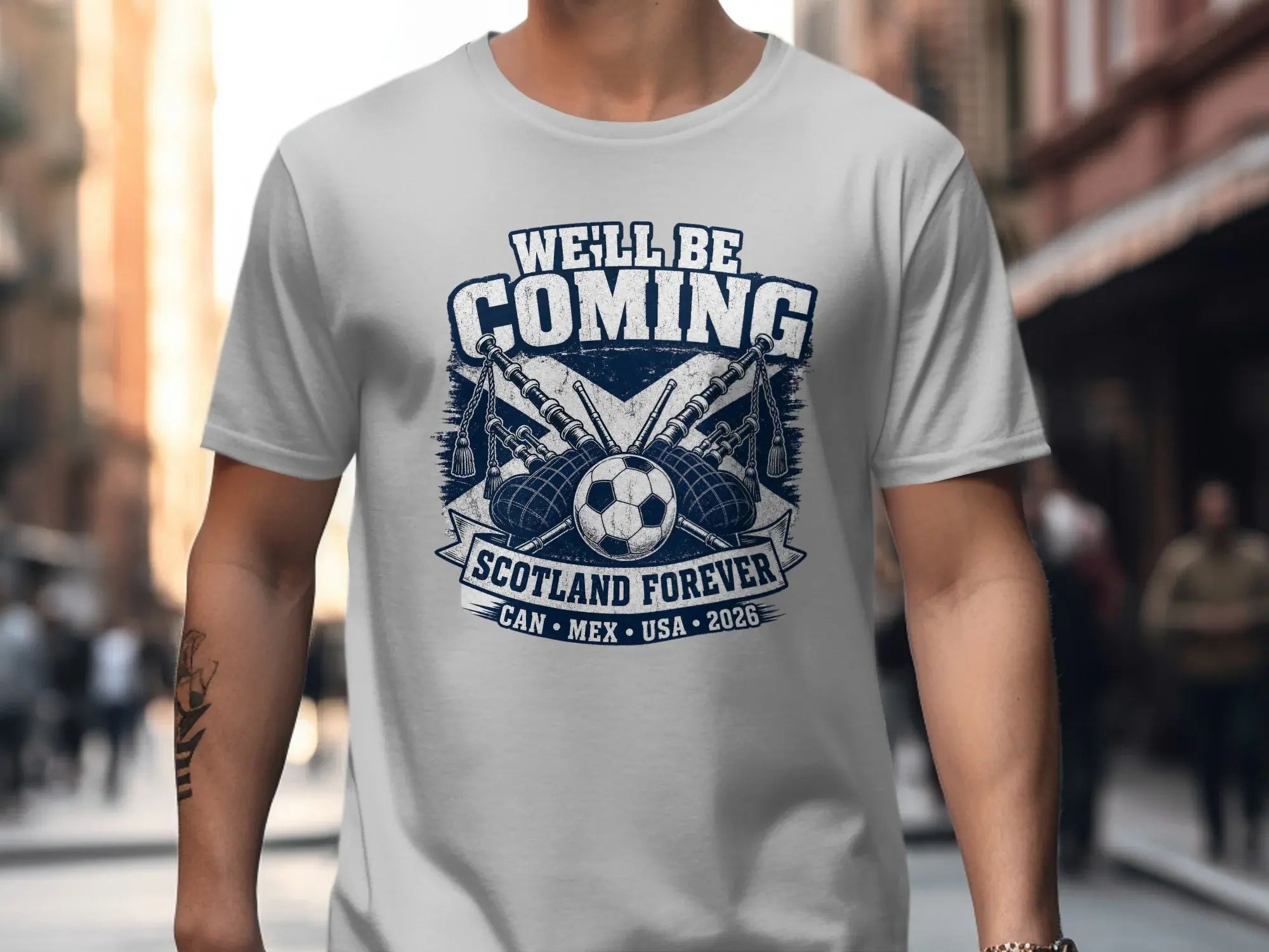 T-shirt with "WE'LL BE COMING" text, bagpipes, and soccer ball.