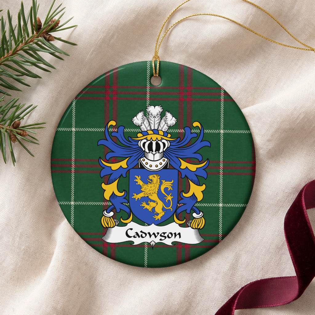 Cadwgon Style 2 ornament on cream fabric with gold string, evergreen and burgundy ribbon; a gold upright lion on a blue shield on Welsh national tartan.