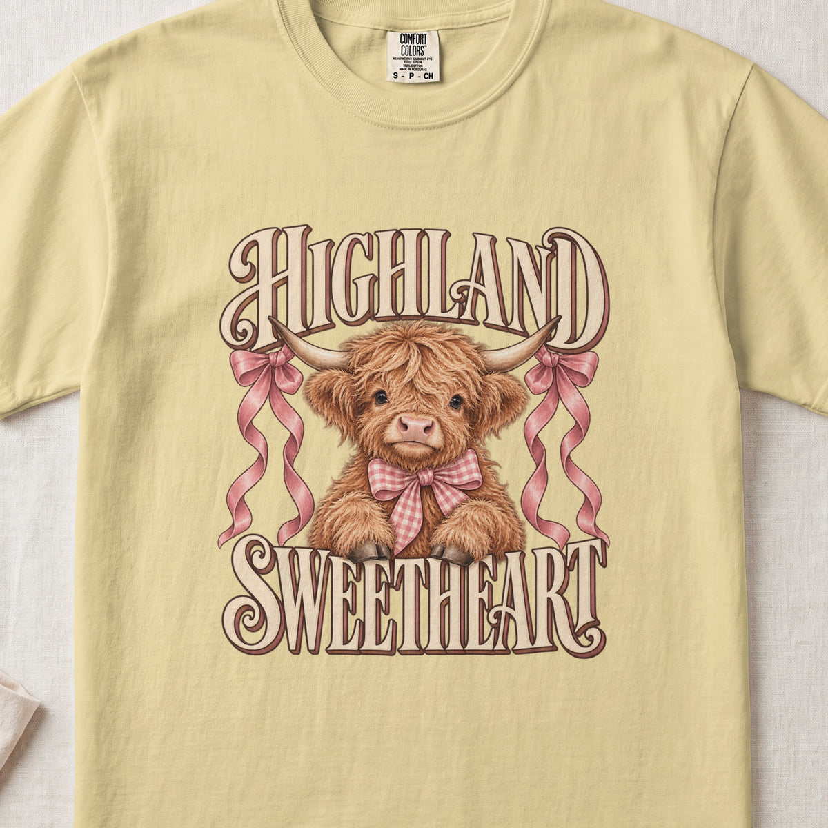 Highland Sweetheart Highland cow design on a Butter Comfort Colors 1717 T-shirt, flat lay