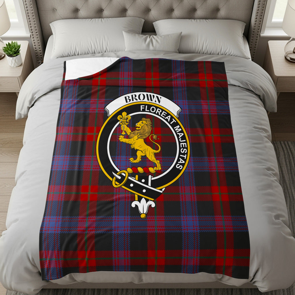 Brown clan crest with lion and Floreat Majestas motto on tartan throw