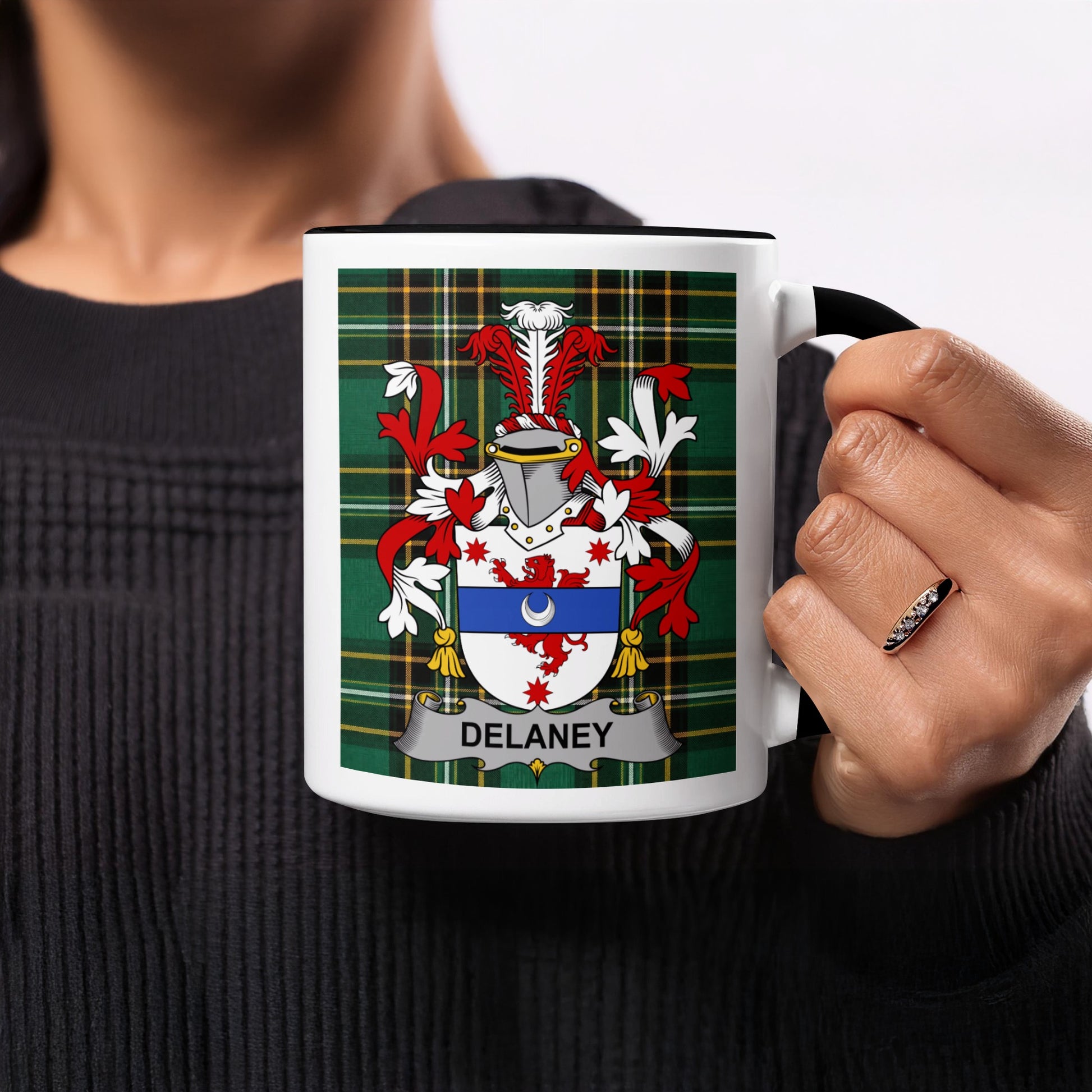 Delaney coat of arms on a black and white mug held by a person.