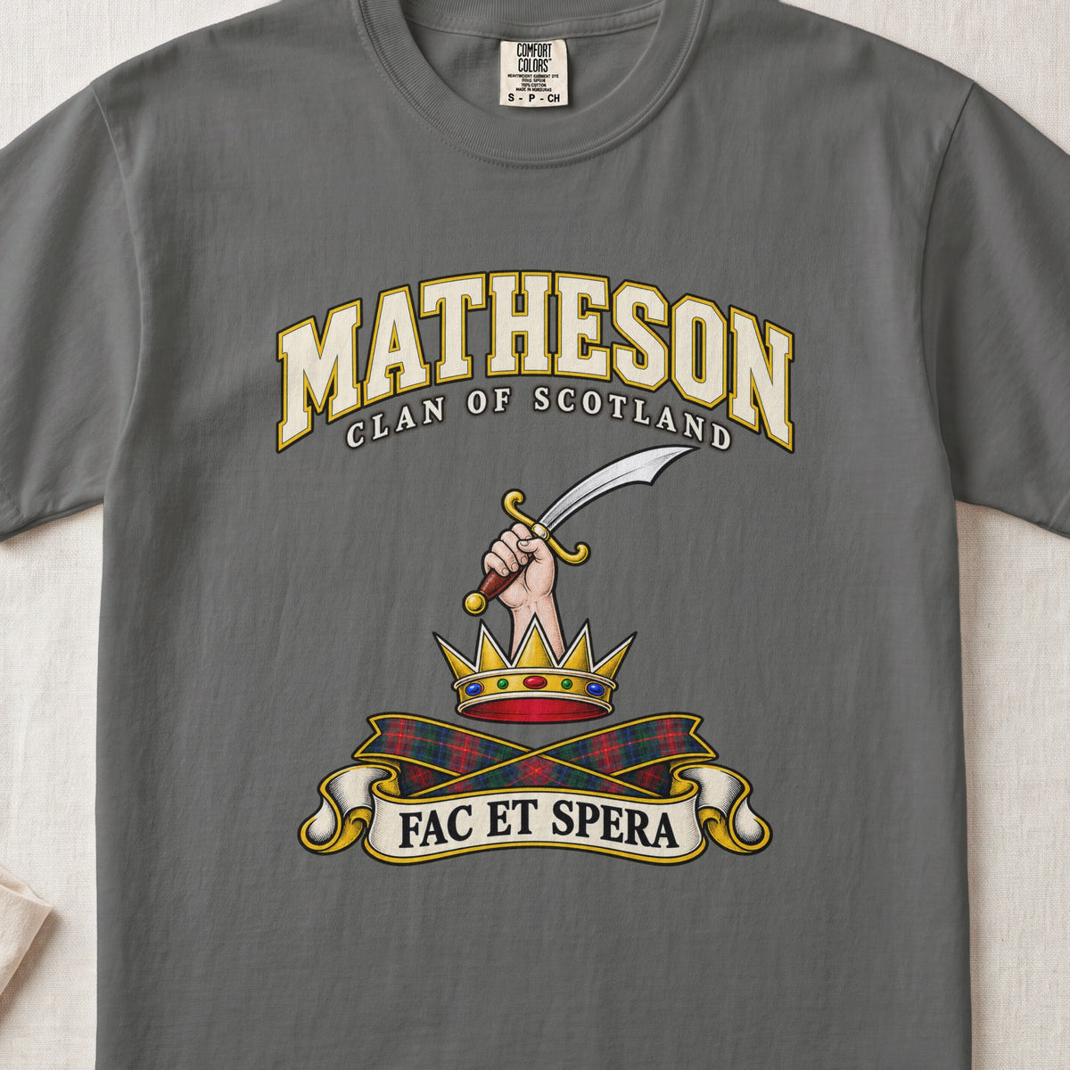 Matheson Scottish clan T-shirt in Pepper, front view with a hand holding a curved sword above a gold crown and motto banner.