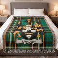 Green plaid blanket with the Lyndon family crest featuring shields and a banner.