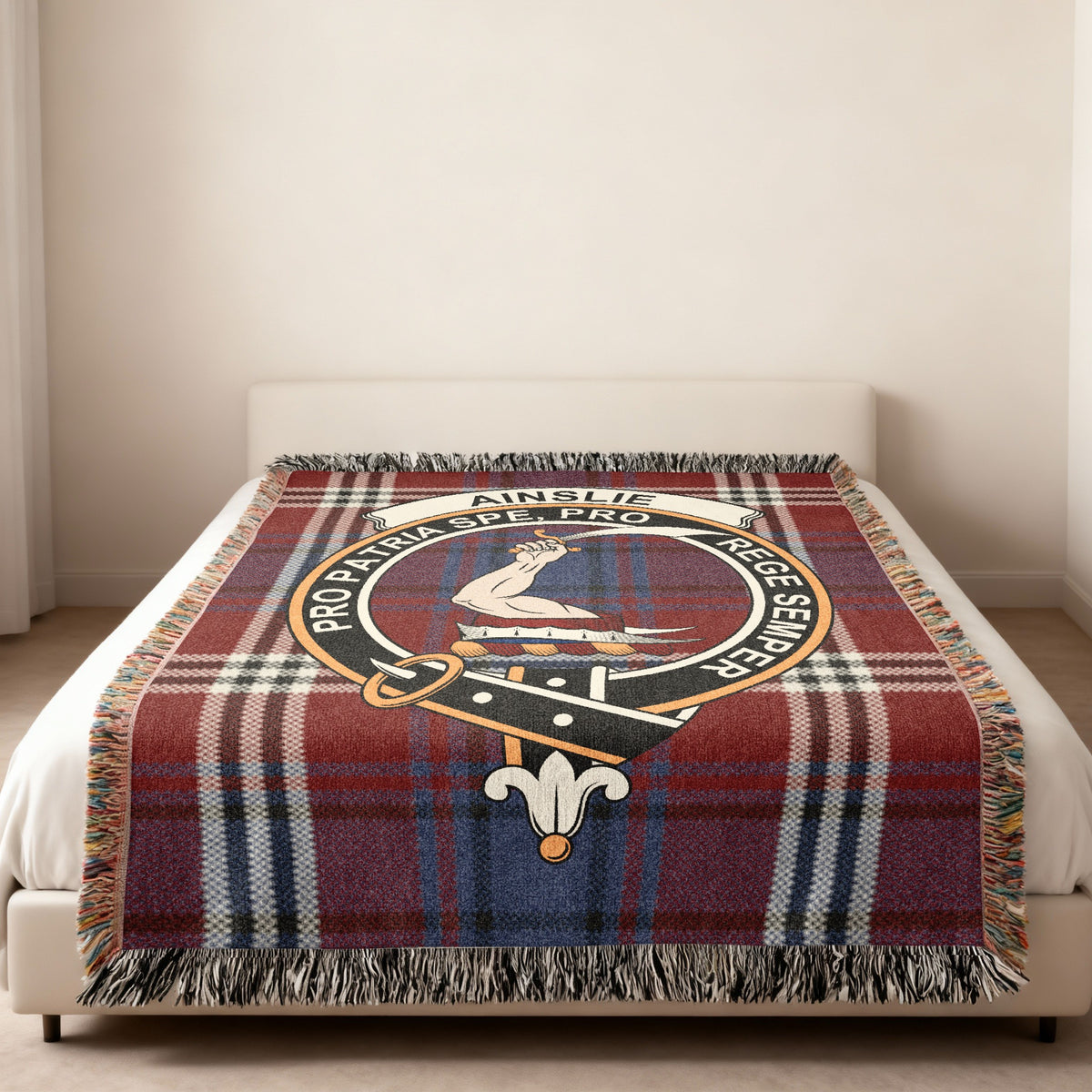 Ainslie Scottish woven blanket spread across a bed, showing the full crest design and tartan background