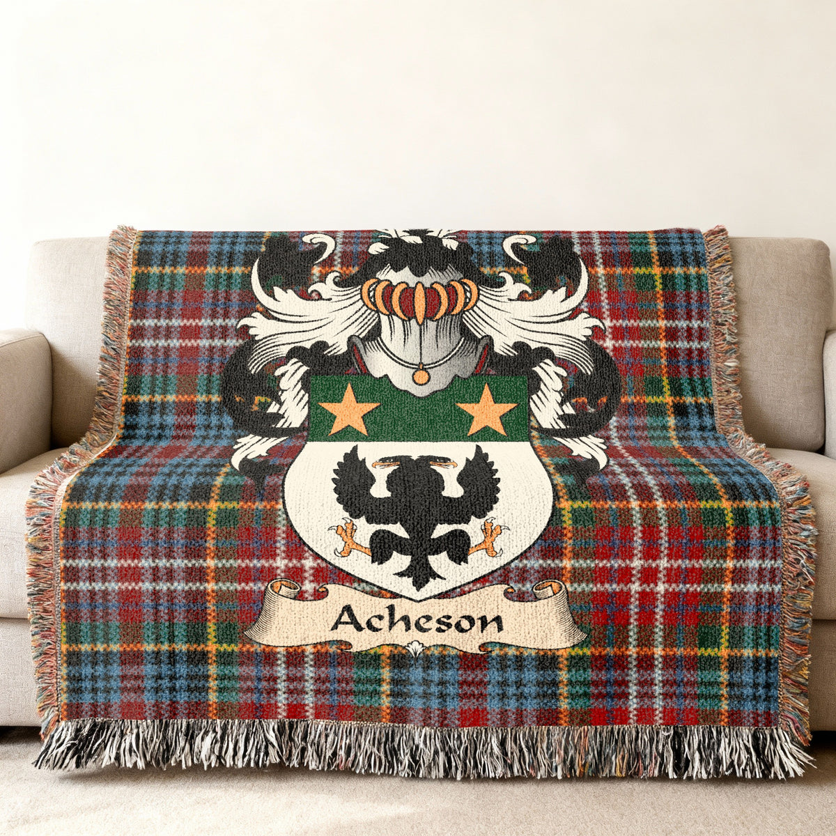 Acheson Scottish family shield woven blanket with Caledonia tartan background on a sofa