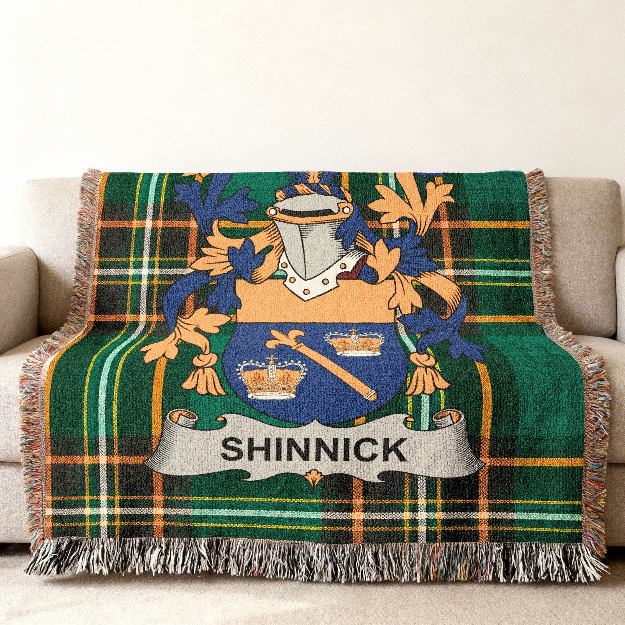 Green tartan woven blanket with the SHINNICK family crest centered on it.