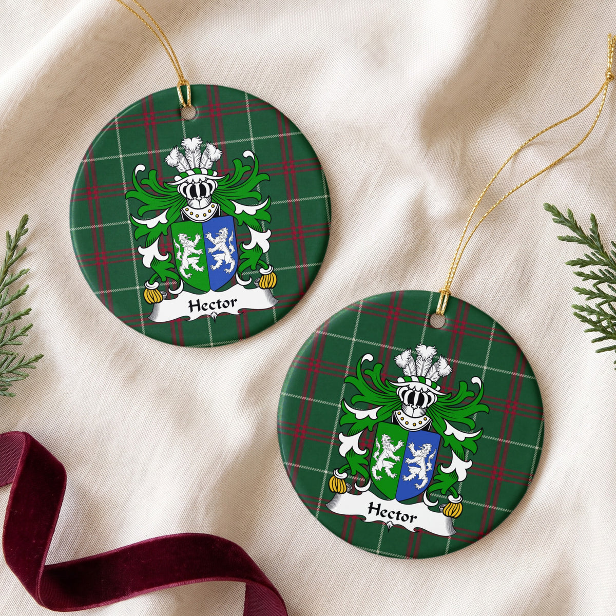 Two Hector ornaments on cream fabric with evergreen and burgundy ribbon; two facing white lions on a green-and-blue divided shield on Welsh national tartan.