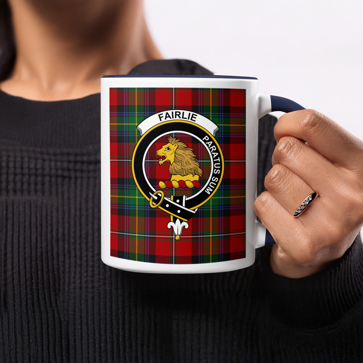 Close-up lifestyle view of Fairlie Scottish family crest artwork on a navy 11 oz accent mug with a tartan background