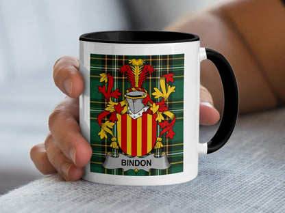 White mug with black rim featuring the Bindon family crest on a green tartan background.