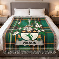 Plaid blanket with personalized WILSON family crest on a bed.