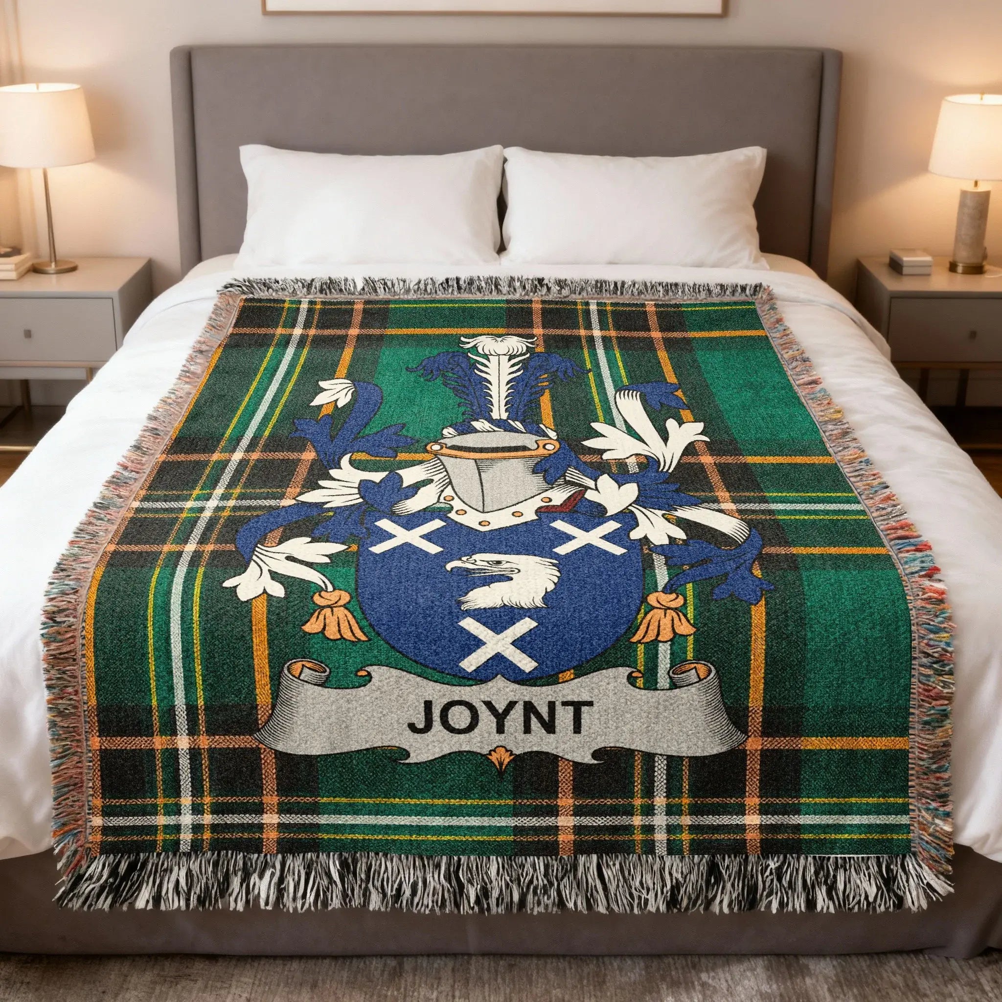 Green and blue plaid blanket with "JOYNT" coat of arms displayed on a bed.