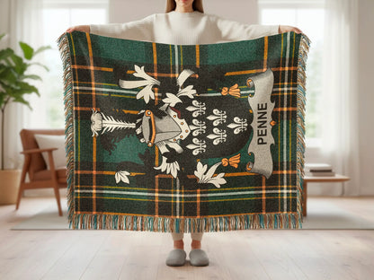 Green plaid throw blanket with crest and PENNE text, held by a person.