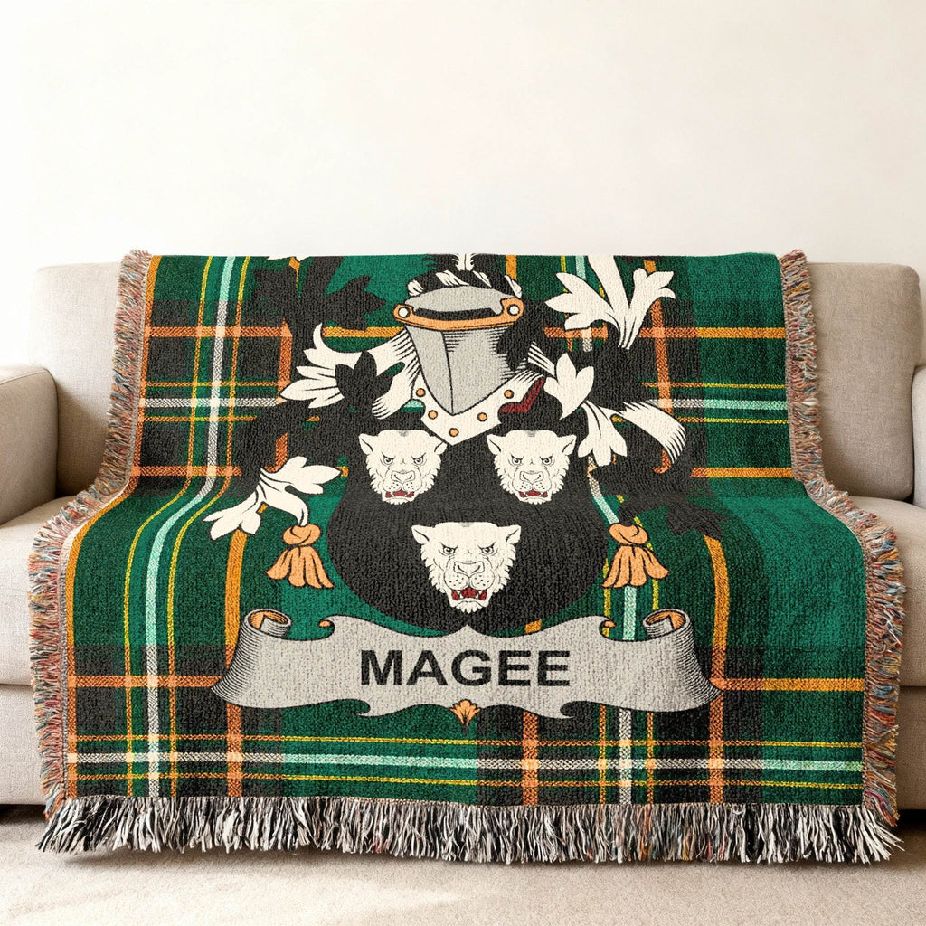 Green tartan blanket with Magee crest displayed on a sofa.