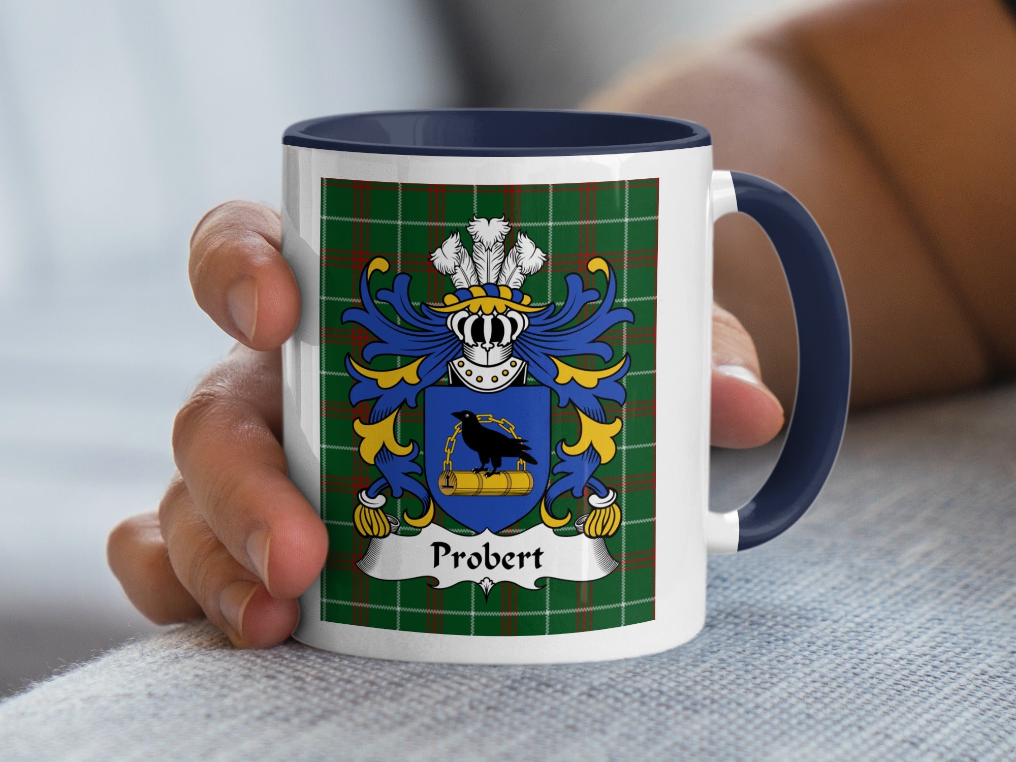 White mug with navy handle and rim displaying Probert family crest on tartan background.