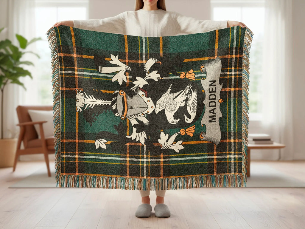 Tartan blanket with crest and "MADDEN" text held by a person.
