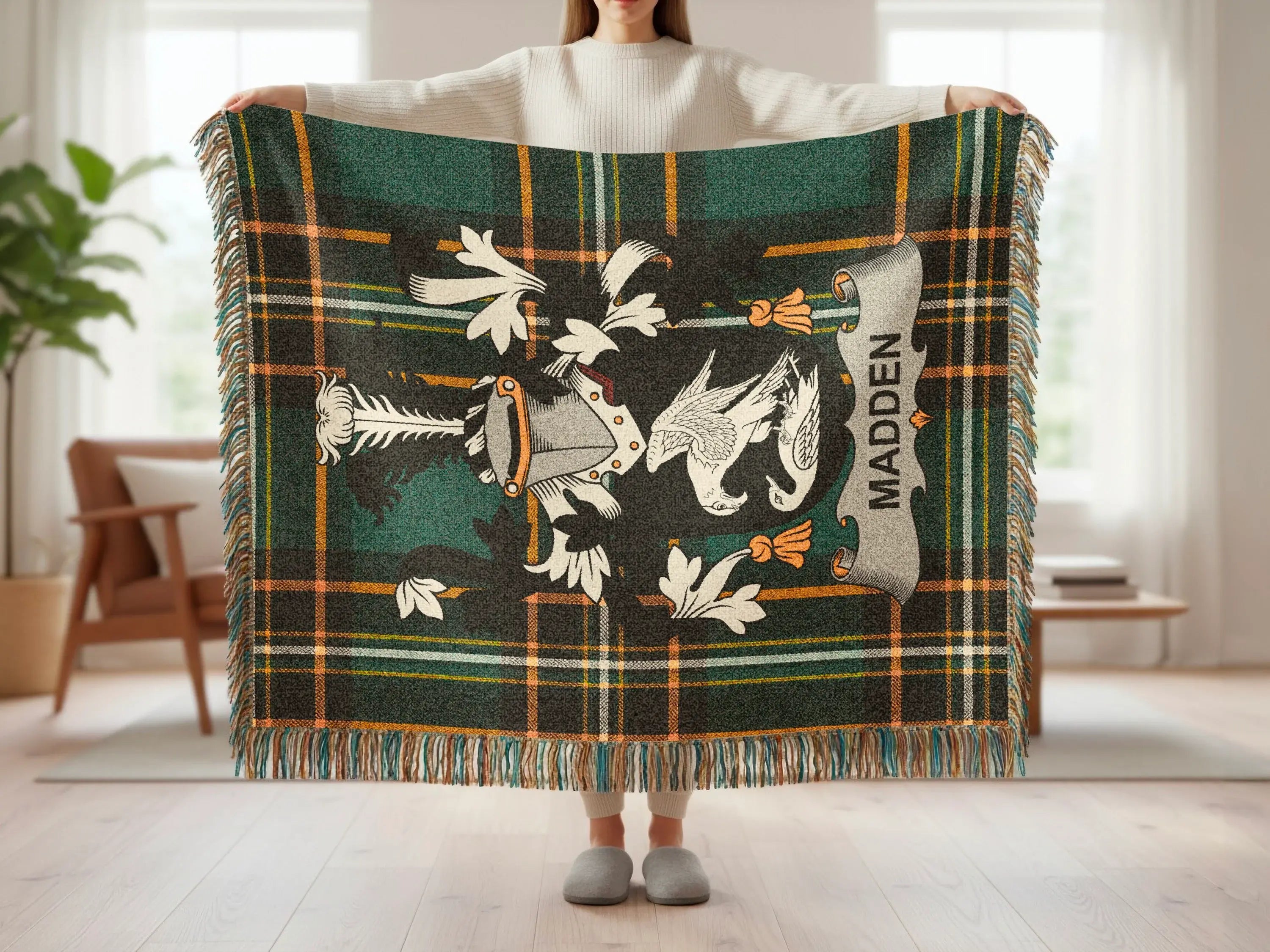 Tartan blanket with crest and "MADDEN" text held by a person.