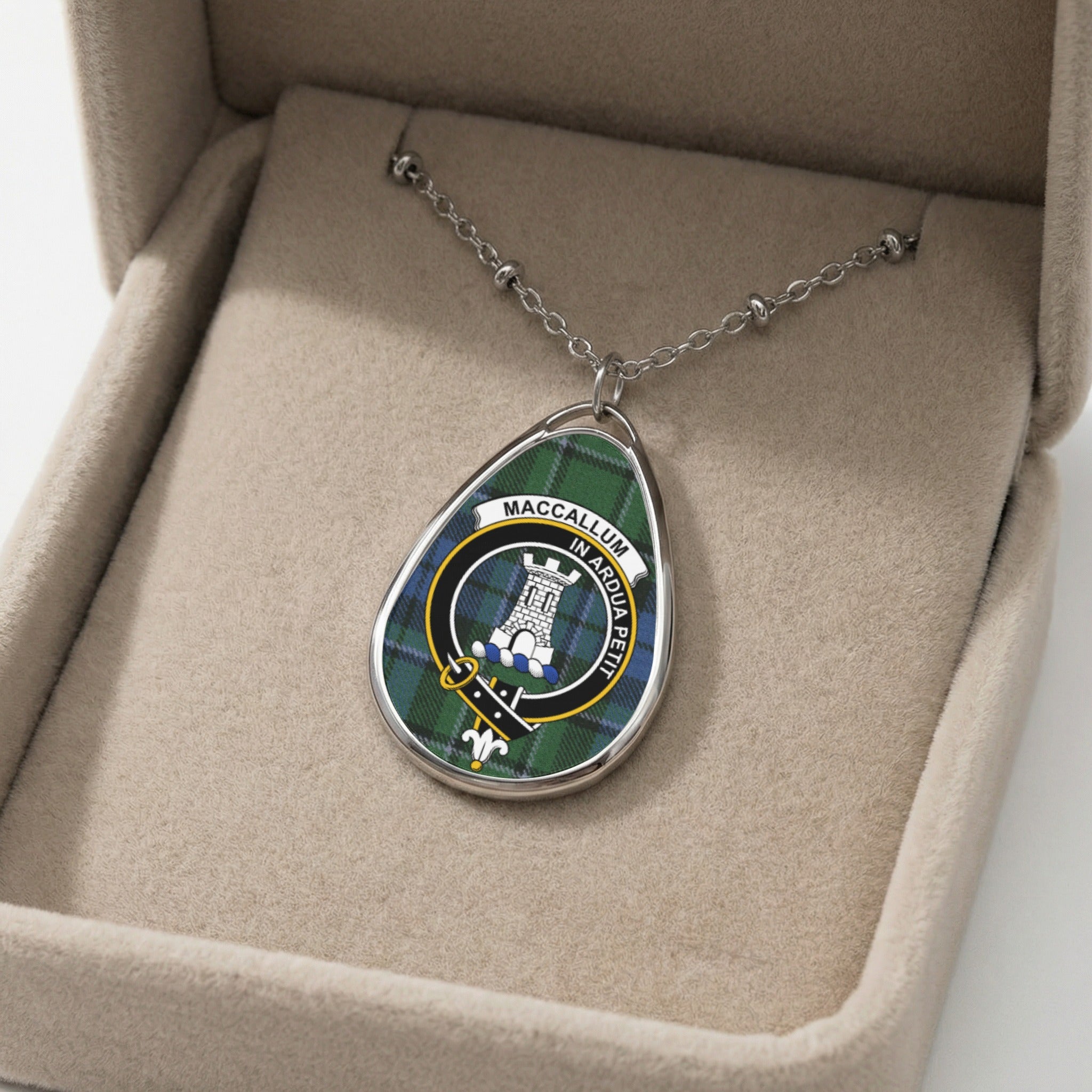 Oval pendant with MacCallum crest and motto "In Ardua Petit" on tartan.
