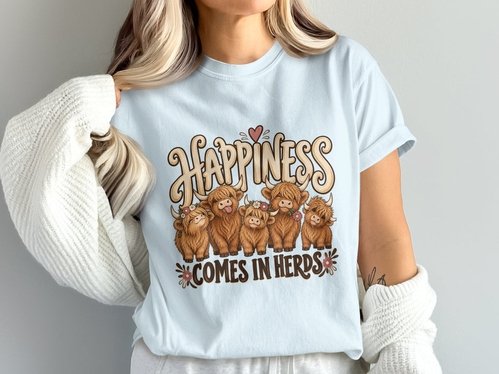 Model wearing the Happiness Comes in Herds Highland cow Comfort Colors T-shirt in Chambray