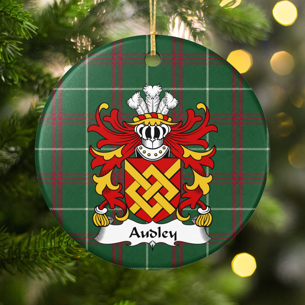 Audley ornament among Christmas tree branches and warm lights; an interlaced gold fret on a red shield on Welsh national tartan.