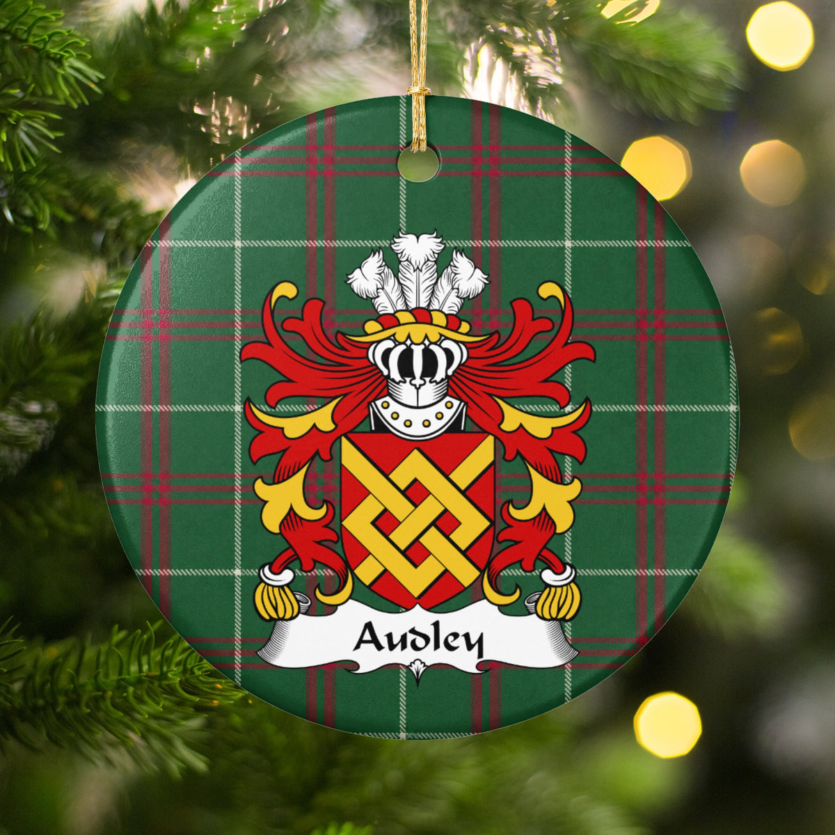 Audley ornament among Christmas tree branches and warm lights; an interlaced gold fret on a red shield on Welsh national tartan.