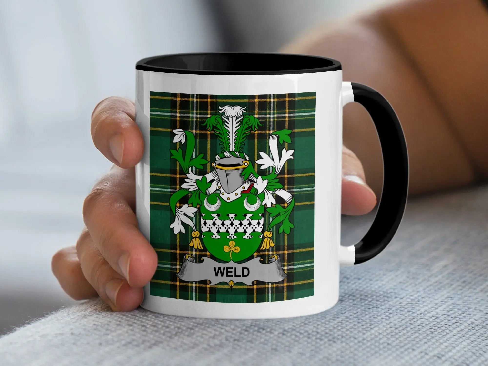 White mug with black rim, featuring a green tartan and a coat of arms with the name WELD.