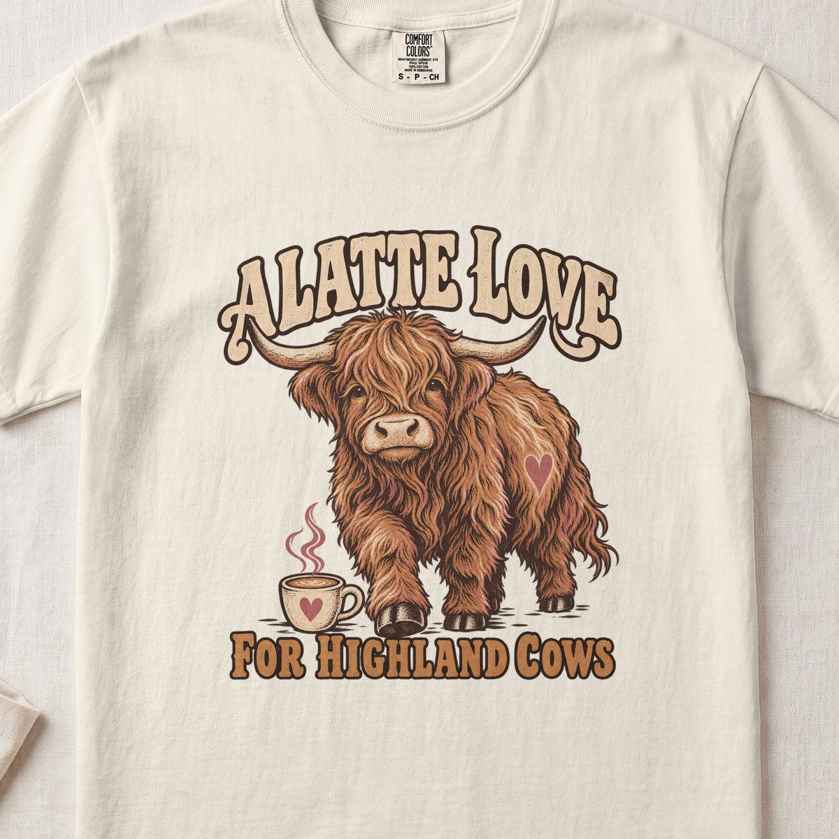 A Latte Love for Highland Cows Highland cow design on an Ivory Comfort Colors 1717 T-shirt, flat lay