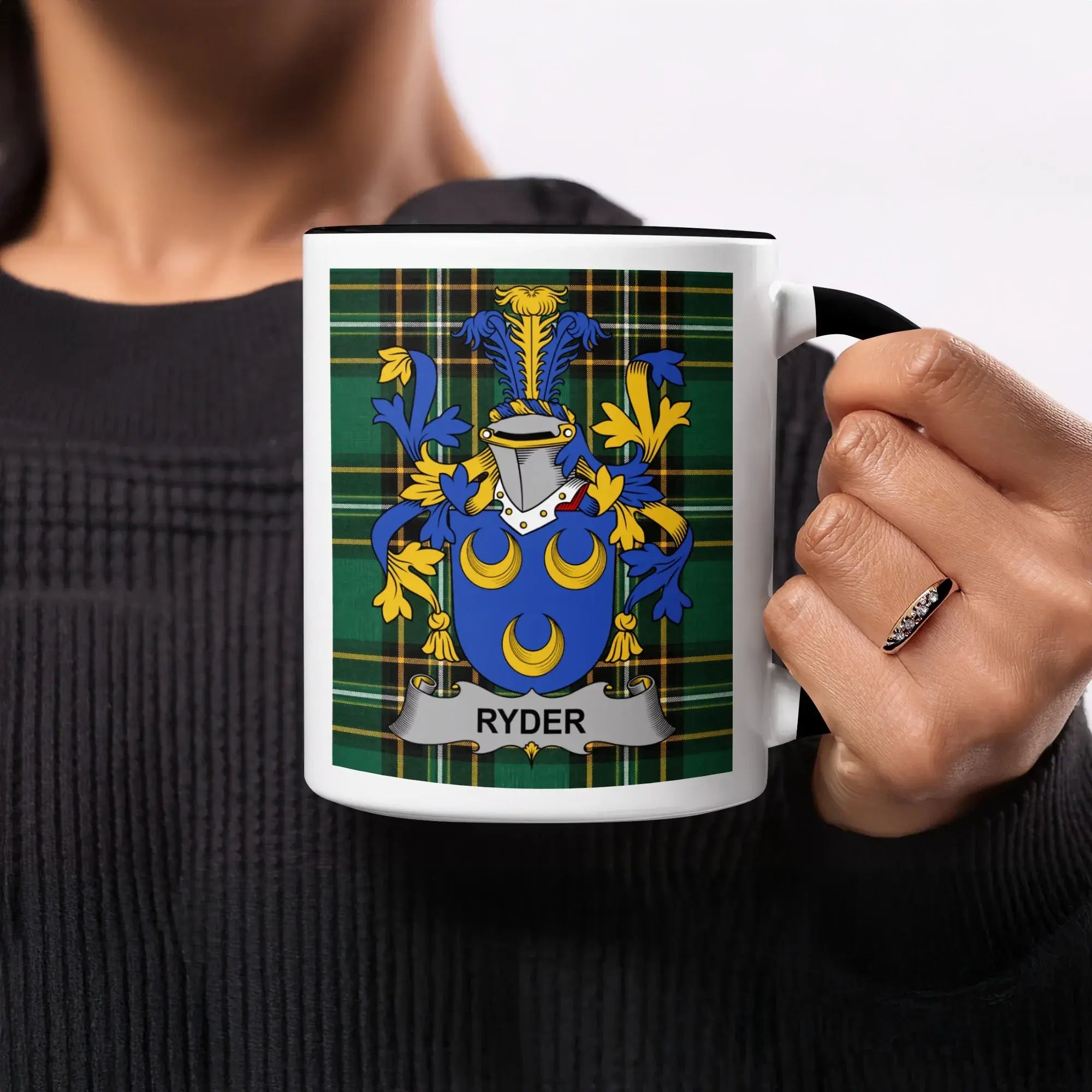 White mug with black handle featuring the Ryder family crest on a tartan background.