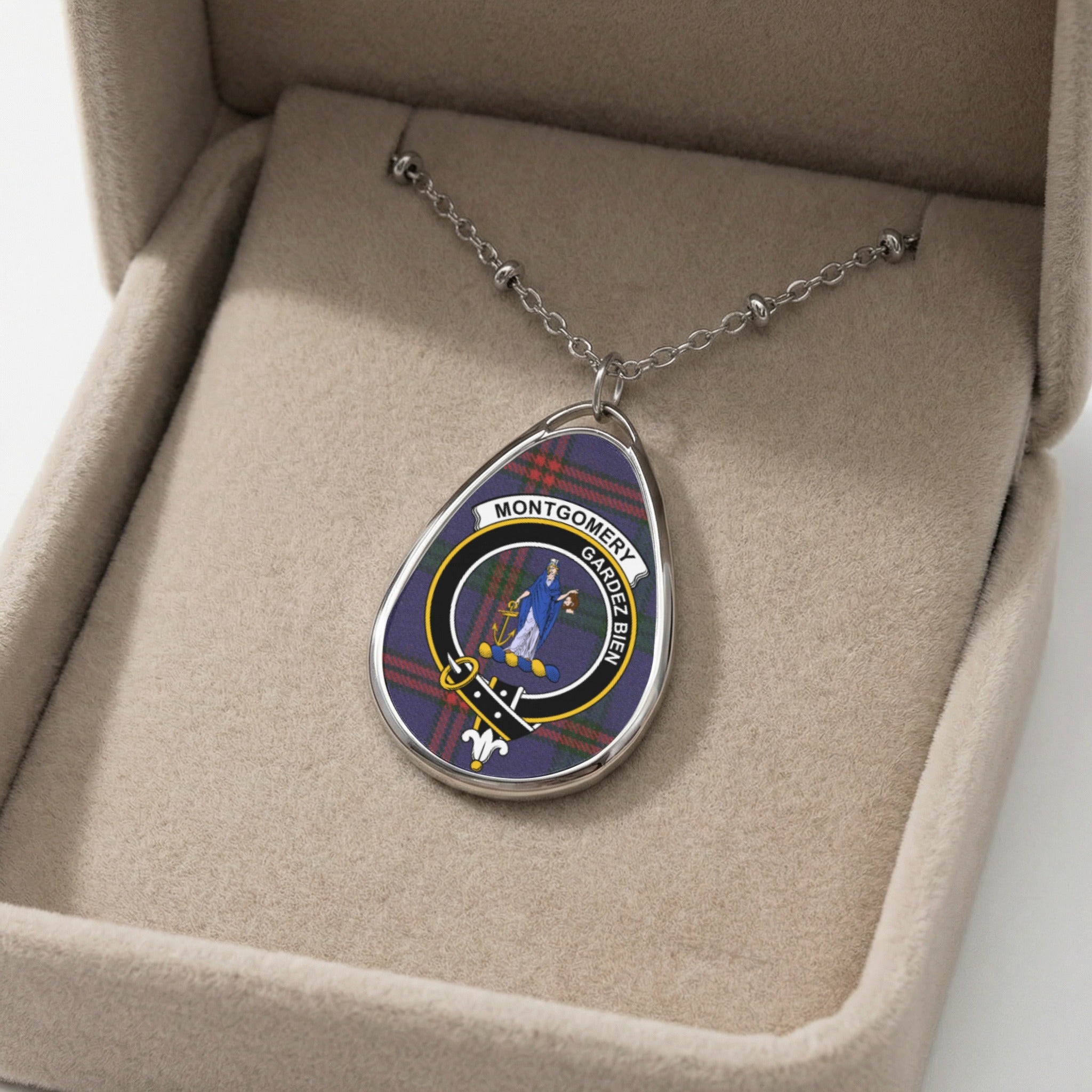 Oval pendant with Montgomery family crest on tartan, on a silver chain in a beige box.