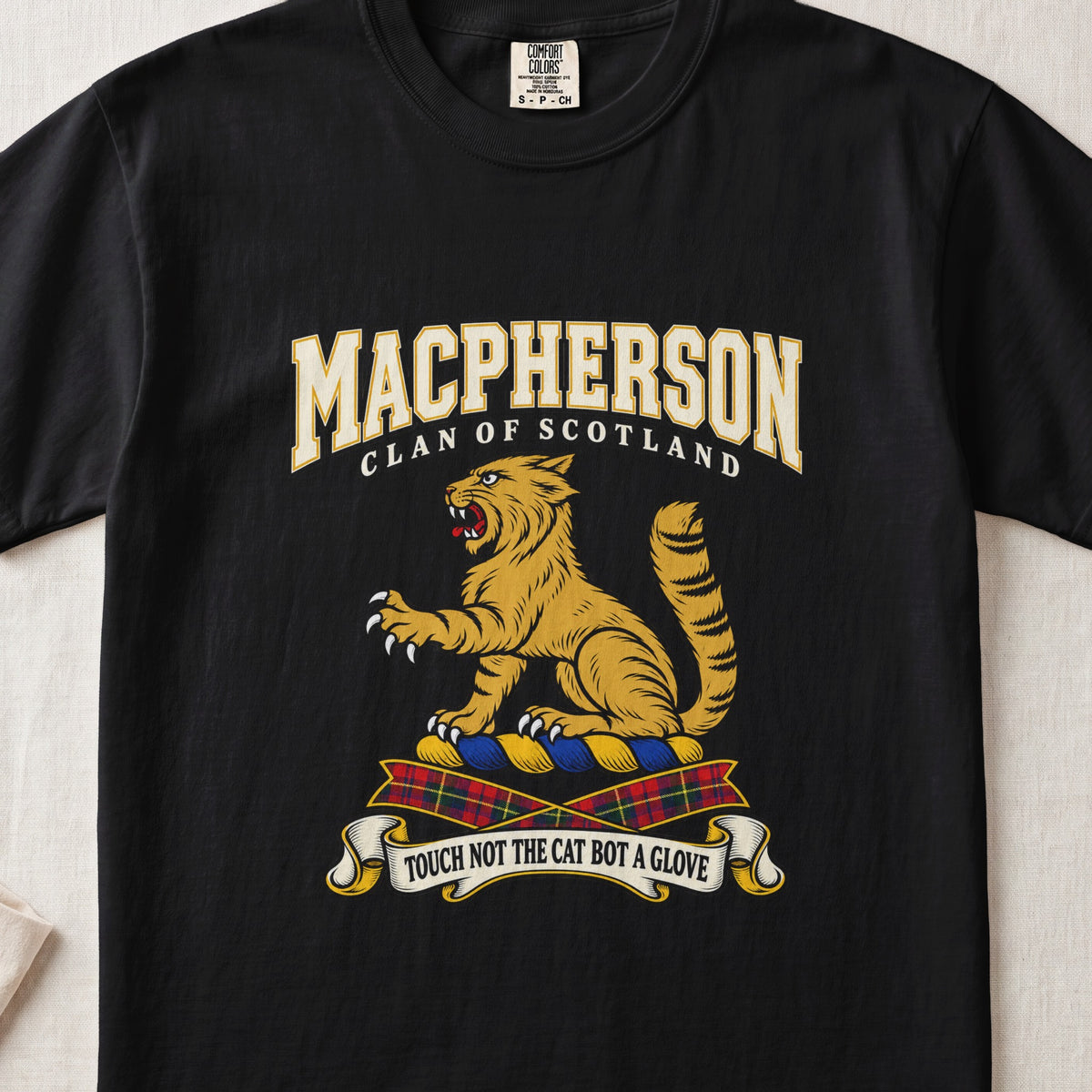 MacPherson graphic T-shirt in Black, front flat lay showing varsity lettering and seated gold wildcat with black stripes, raised paw and upright tail.