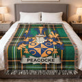 Green plaid throw blanket with Peacocke family crest displayed.