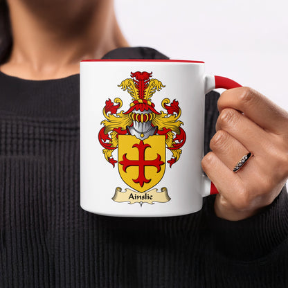 White mug with red rim and handle featuring the Ainslie coat of arms.