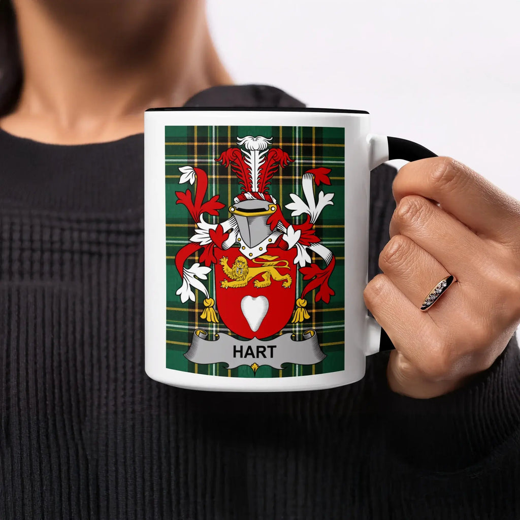 Mug with Hart family crest on tartan background, held by a person.