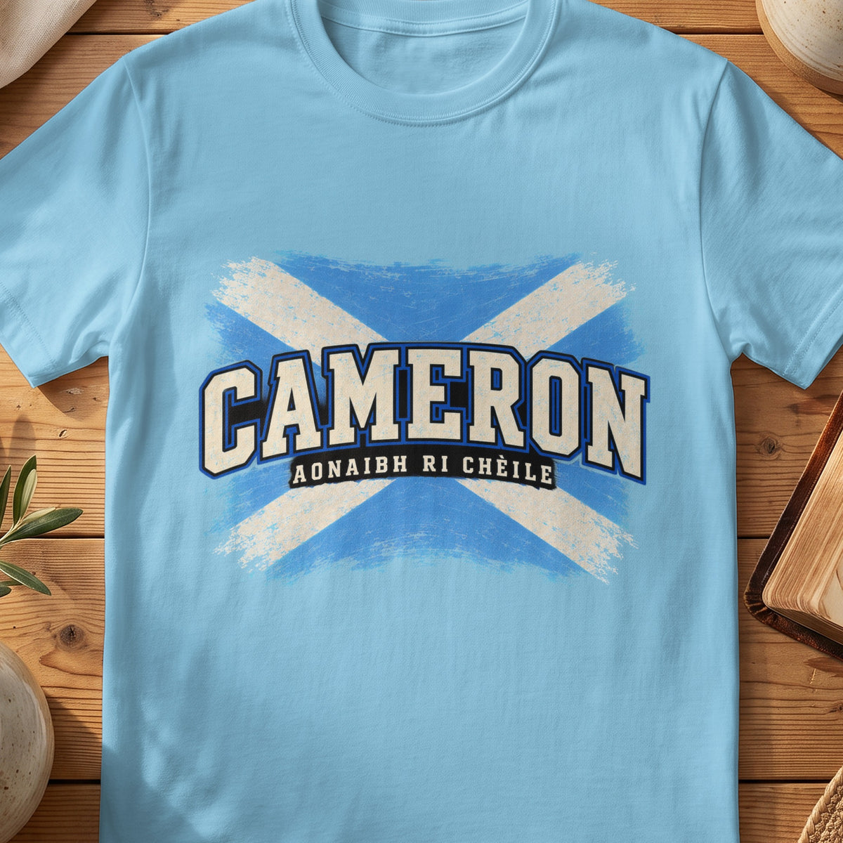 Cameron Scottish Saltire T-shirt in Sky, with distressed blue and cream flag and “Aonaibh Ri Chèile” lettering.
