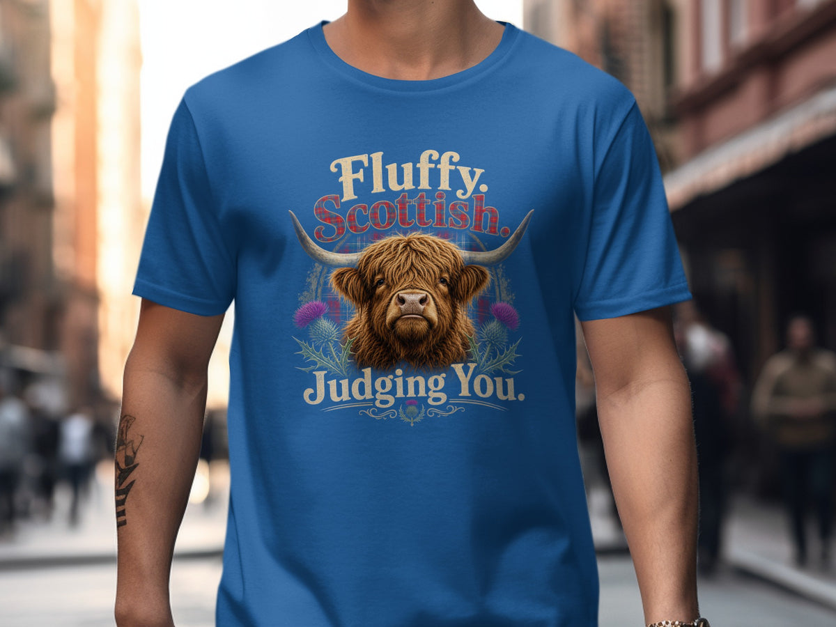 Blue t-shirt with Highland cow graphic and text "Fluffy. Scottish. Judging You."