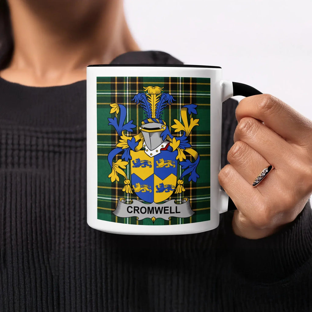 Coat of arms with "Cromwell" text on a white mug held by a person.