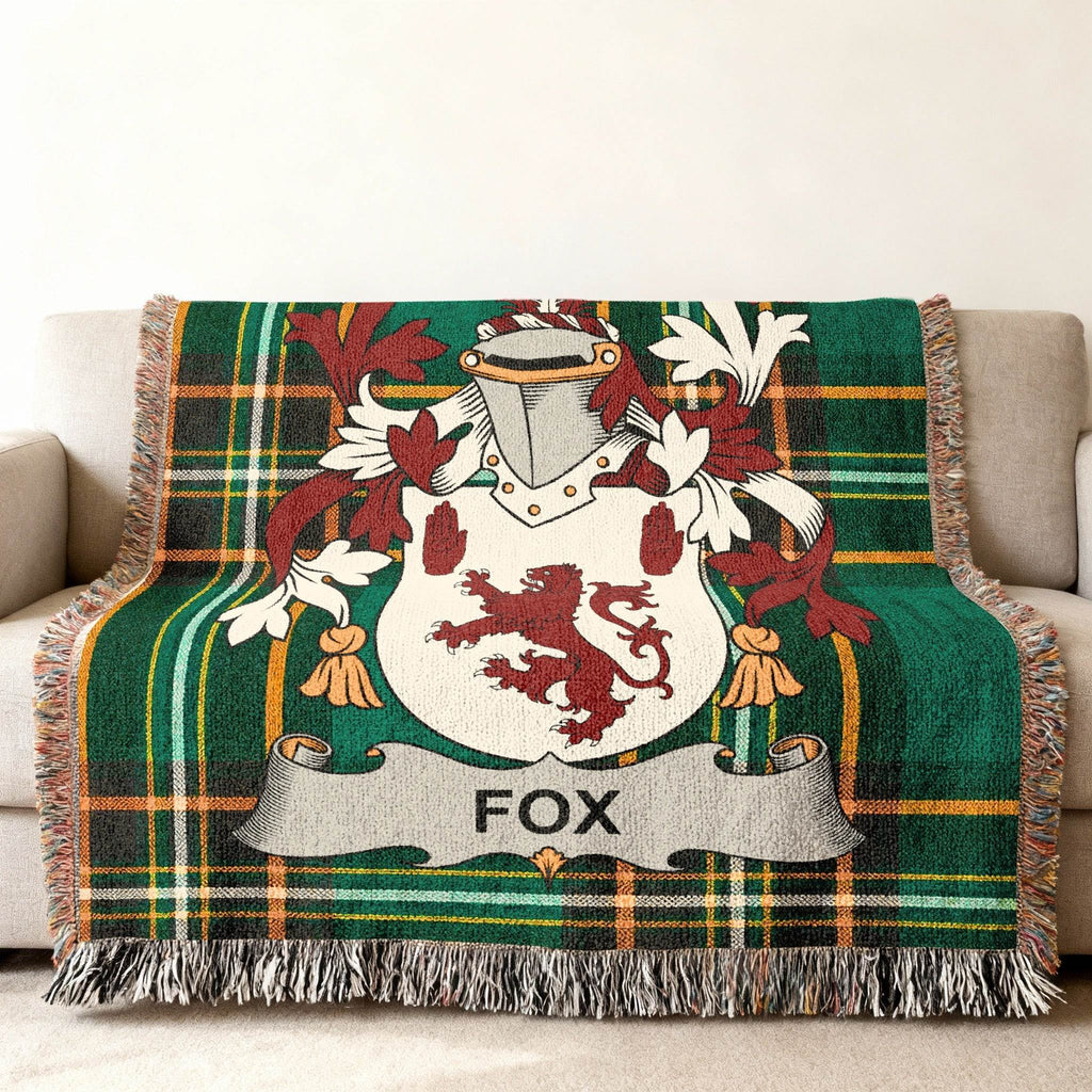Woven throw blanket with green plaid pattern and a central coat of arms with the name FOX.