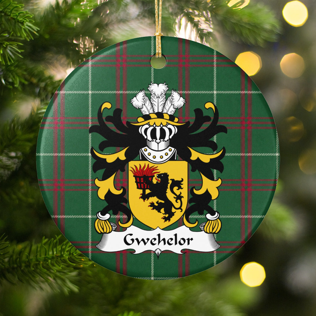 Gwehelor ornament hanging in a Christmas tree with warm lights; a black lion holding a flaming basket on a gold shield on Welsh national tartan.