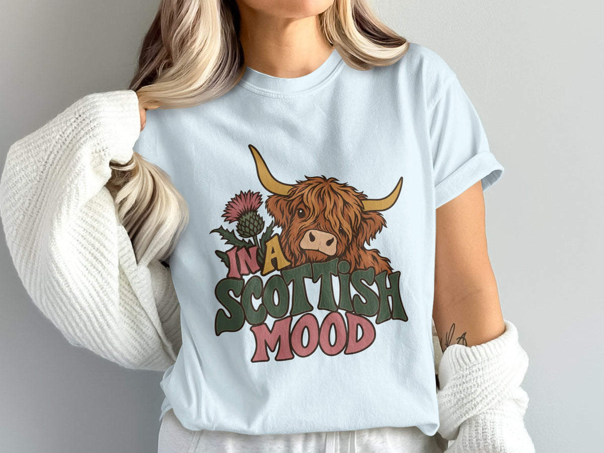 Model wearing the In a Scottish Mood Highland cow Comfort Colors T-shirt in Chambray