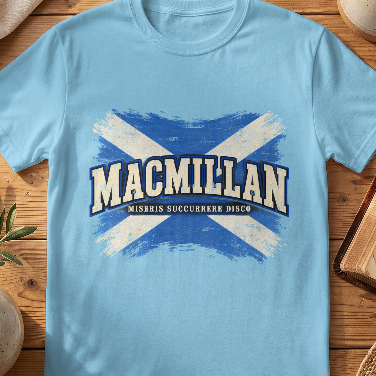 MacMillan Scottish Saltire T-shirt in Sky, with distressed blue and cream flag and “Miseris Succurrere Disco” lettering.