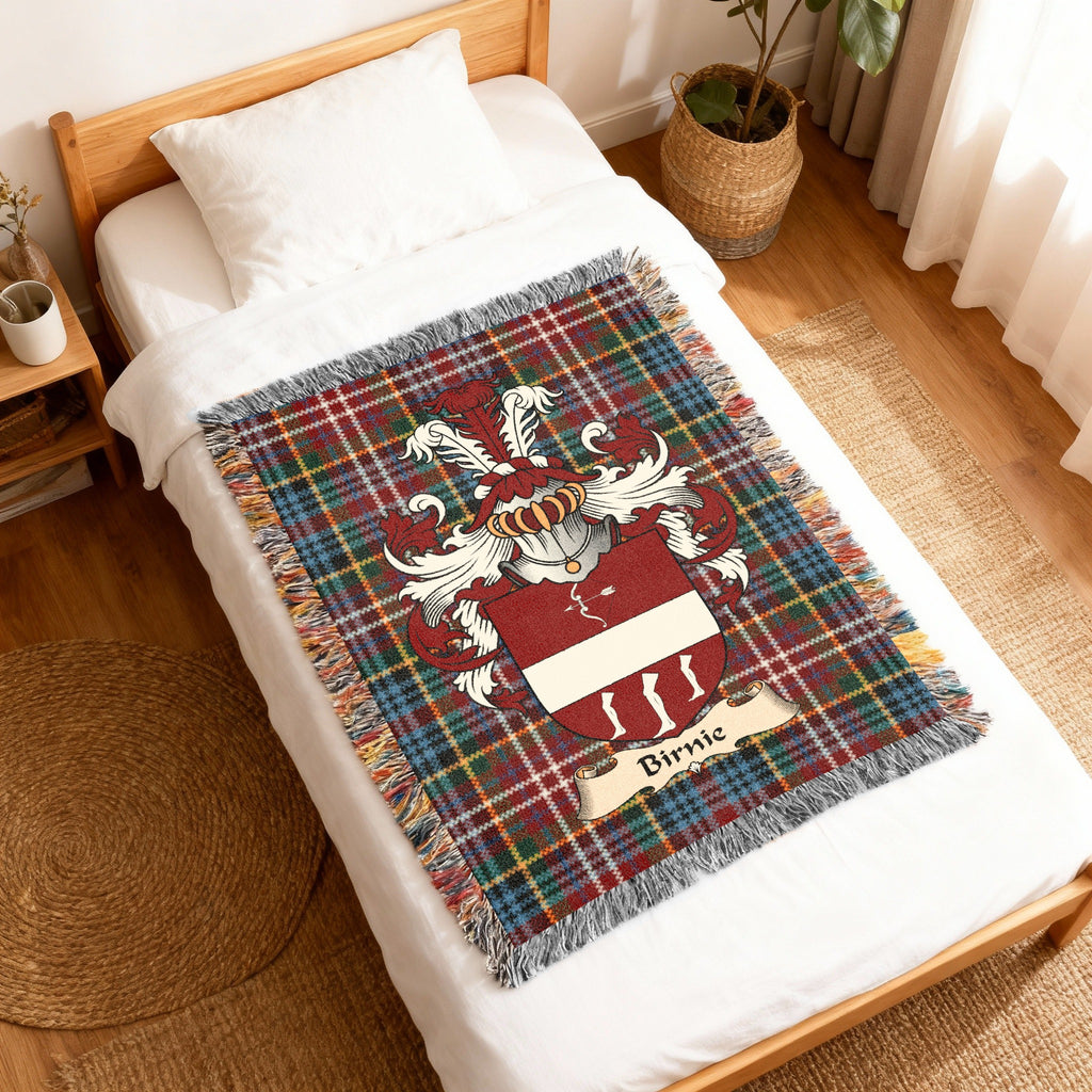 Birnie Scottish family shield woven blanket with Caledonia tartan background, displayed on a bed