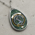 Macneil clan crest pendant on a silver chain with plaid background and "Vincere Aut Mori" motto.