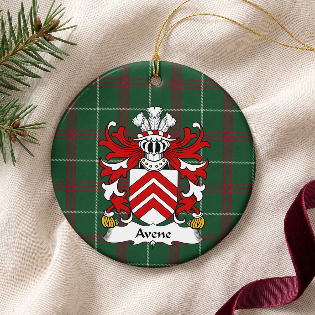 Avene ceramic ornament with gold string on cream fabric; three red chevrons on a white shield on Welsh national tartan.