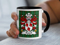 Mug with Russell family crest on green tartan background held by a hand.