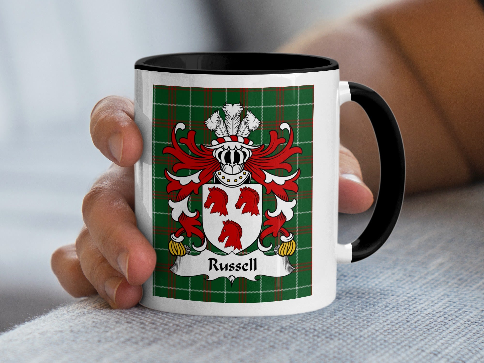 Mug with Russell family crest on green tartan background held by a hand.