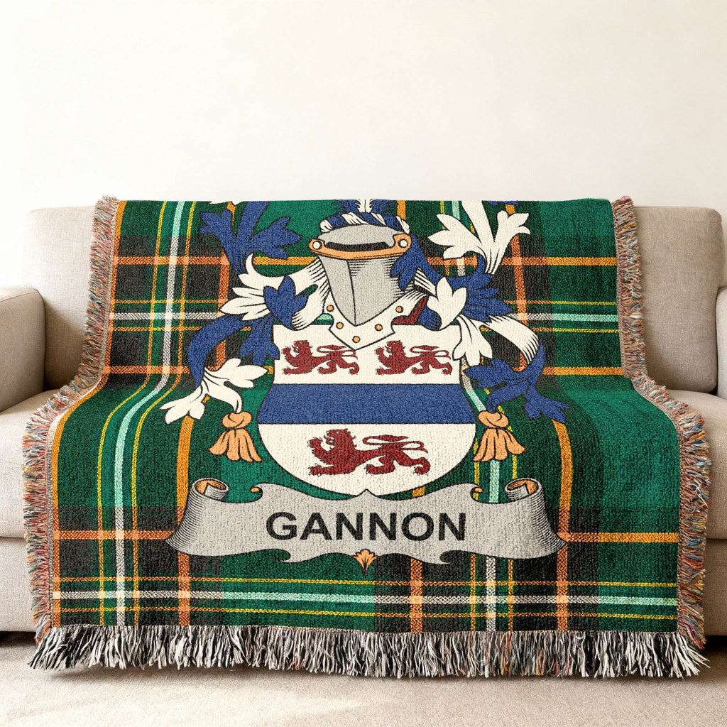 Green tartan blanket with Gannon family crest on a sofa.