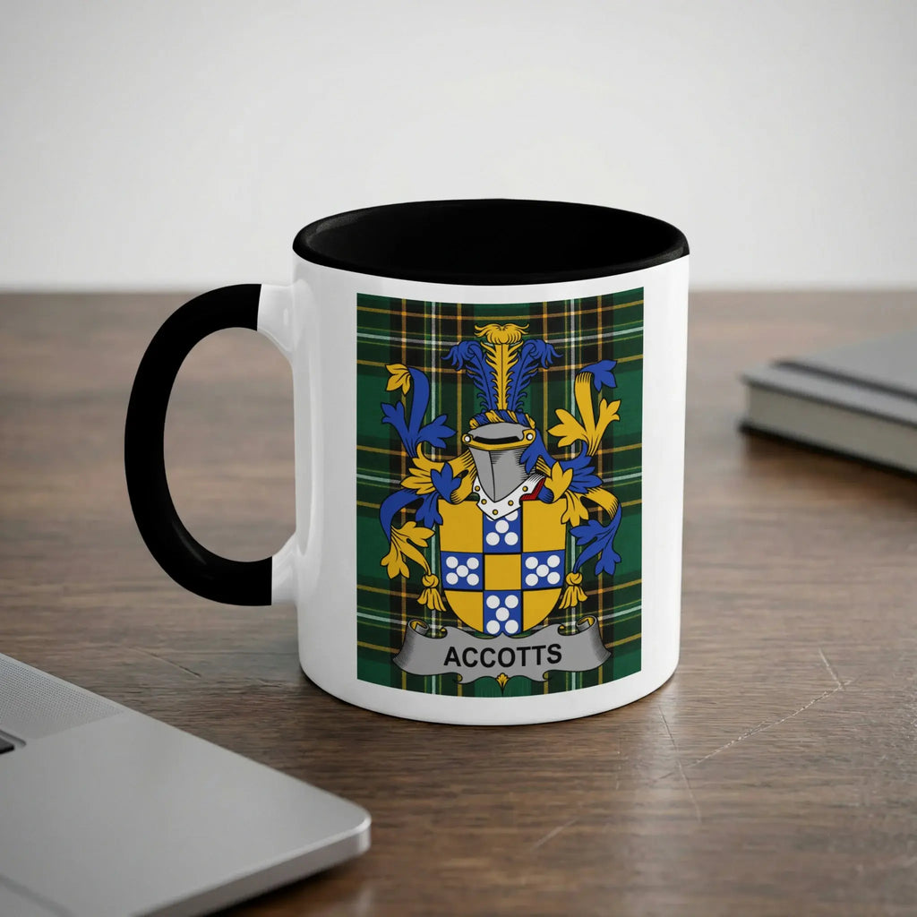 White mug with black rim and handle featuring the "ACCOTTS" coat of arms on plaid background.