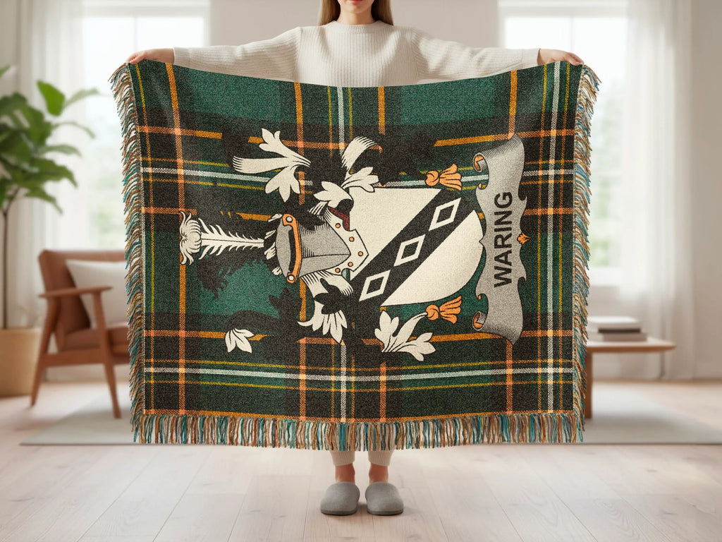 Green tartan blanket with Waring family crest and fringe held up by a person.